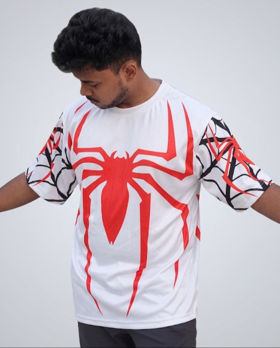 A man wearing a white oversized t-shirt with a large red spider logo on the chest and black web patterns on the sleeves.