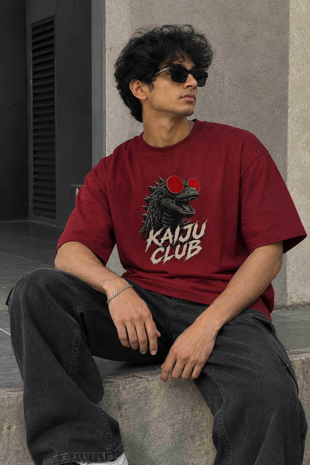 Model wearing red oversized Kaiju Club t-shirt with bold kaiju graphic and distressed lettering