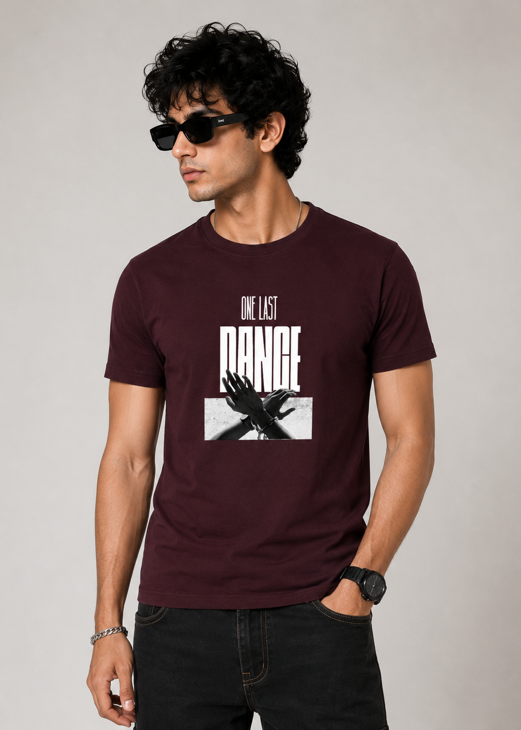 Male model wearing a maroon premium cotton graphic t-shirt featuring the "One Last Dance" typography with a monochrome artistic hand illustration on the front. Ideal for casual and streetwear fashion.