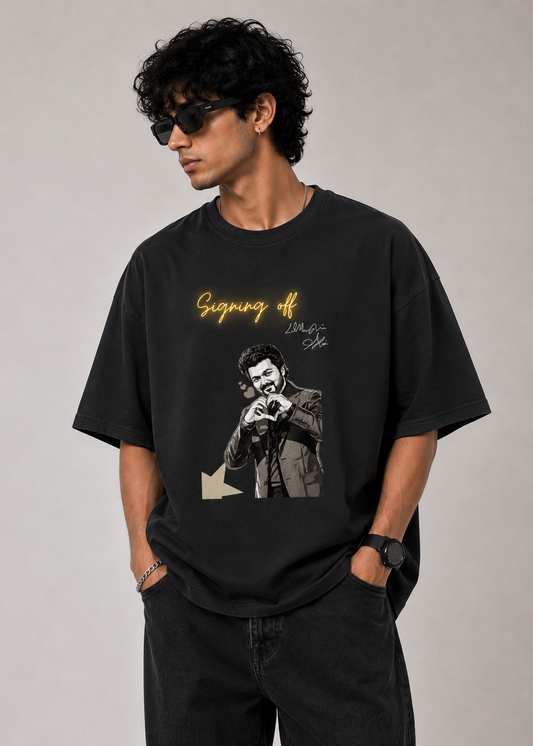 Male model wearing a black oversized graphic t-shirt featuring the "Signing Off" design with glowing handwritten typography and monochrome artwork. Premium unisex streetwear t-shirt by LowKey.