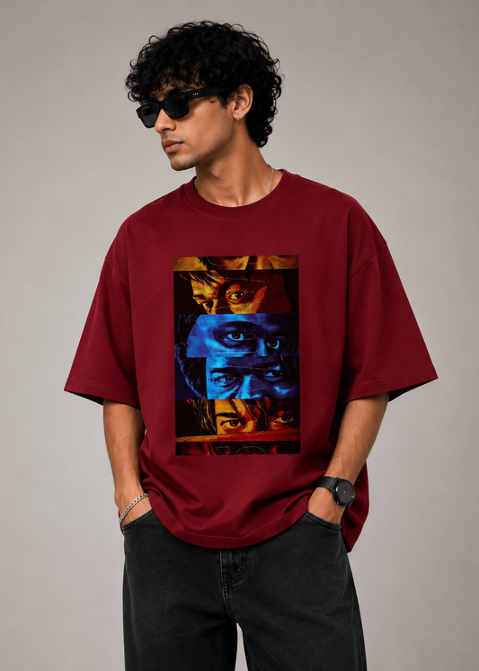 A model wearing a red oversized premium cotton t-shirt featuring a bold multi-color eye collage graphic print on the front. Modern unisex streetwear by LowKey.