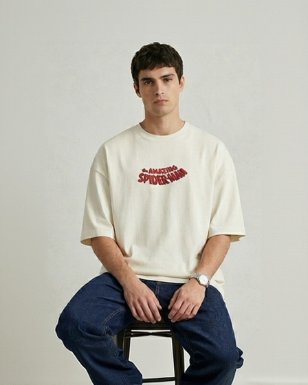 model wearing Front view of an off-white oversized t-shirt featuring a small "The Amazing Spider-Man" red and blue logo on the chest.